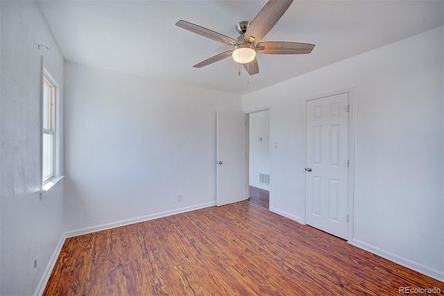 unfurnished room with ceiling fan, wood finished floors, visible vents, and baseboards