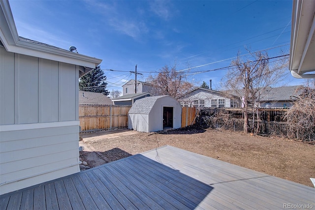 wooden deck featuring an outdoor structure, a fenced backyard, and a storage shed