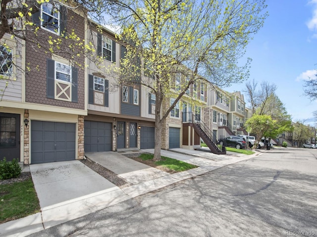 view of building exterior with driveway, a residential view, and an attached garage