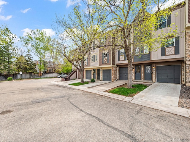 multi unit property featuring driveway, an attached garage, and fence