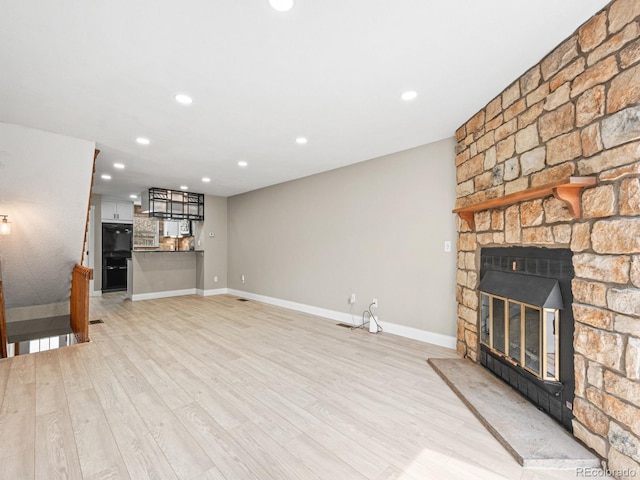 unfurnished living room with a fireplace, baseboards, recessed lighting, and light wood-type flooring