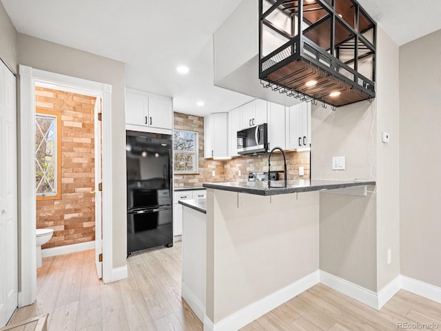 kitchen featuring freestanding refrigerator, stainless steel microwave, light wood-style flooring, a peninsula, and recessed lighting