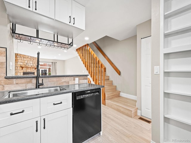 kitchen featuring dishwasher, baseboards, a sink, white cabinetry, and built in shelves