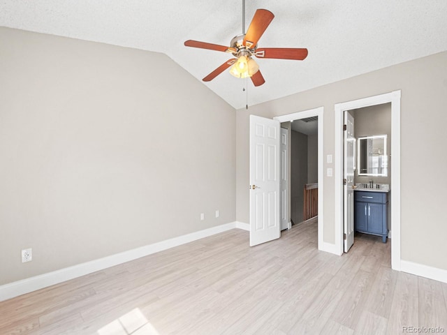 unfurnished bedroom featuring light wood-style flooring, lofted ceiling, baseboards, ceiling fan, and a sink