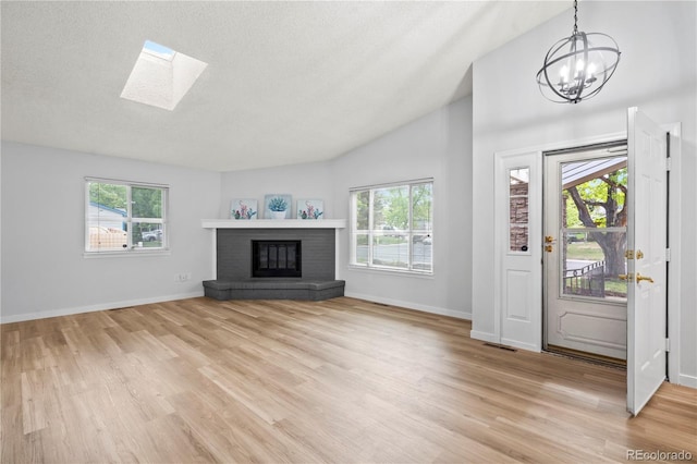 2090 S Fairplay St, Aurora, CO 80014 - unfurnished living room featuring a chandelier, light wood finished floors, baseboards, a textured ceiling, and a skylight