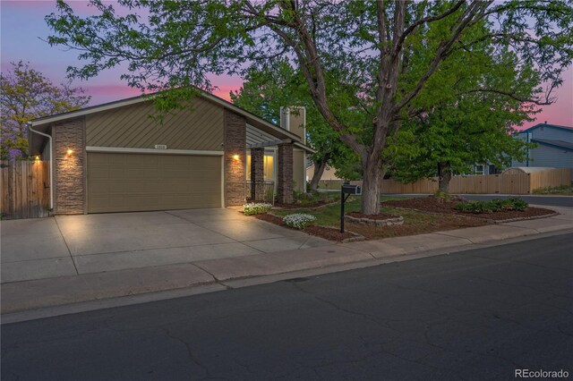2090 S Fairplay St, Aurora, CO 80014 - view of front facade featuring an attached garage, driveway, a chimney, stone siding, and a gate