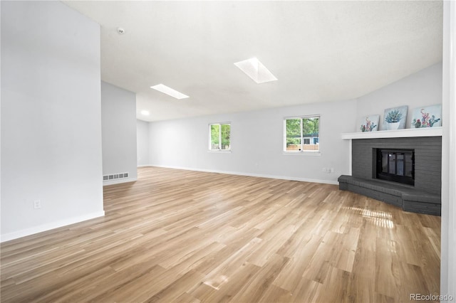 2090 S Fairplay St, Aurora, CO 80014 - unfurnished living room with a skylight, light wood-type flooring, vaulted ceiling, a fireplace, and baseboards