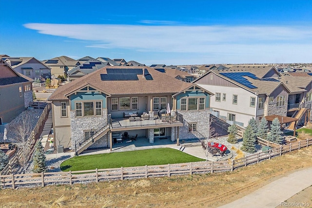 back of property featuring a residential view, stairs, roof mounted solar panels, a fenced backyard, and a patio