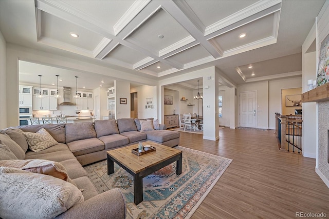 living area featuring crown molding, wood finished floors, coffered ceiling, and a chandelier