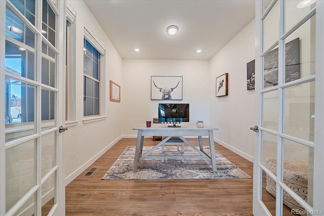 office space with wood finished floors, visible vents, and baseboards