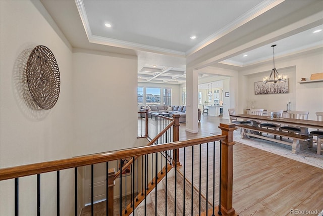 hallway with an upstairs landing, ornamental molding, coffered ceiling, wood finished floors, and an inviting chandelier