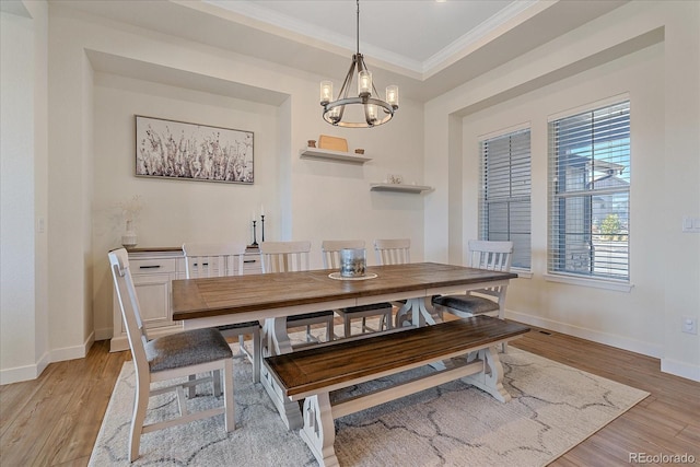 dining area with baseboards, a chandelier, light wood-type flooring, a tray ceiling, and ornamental molding