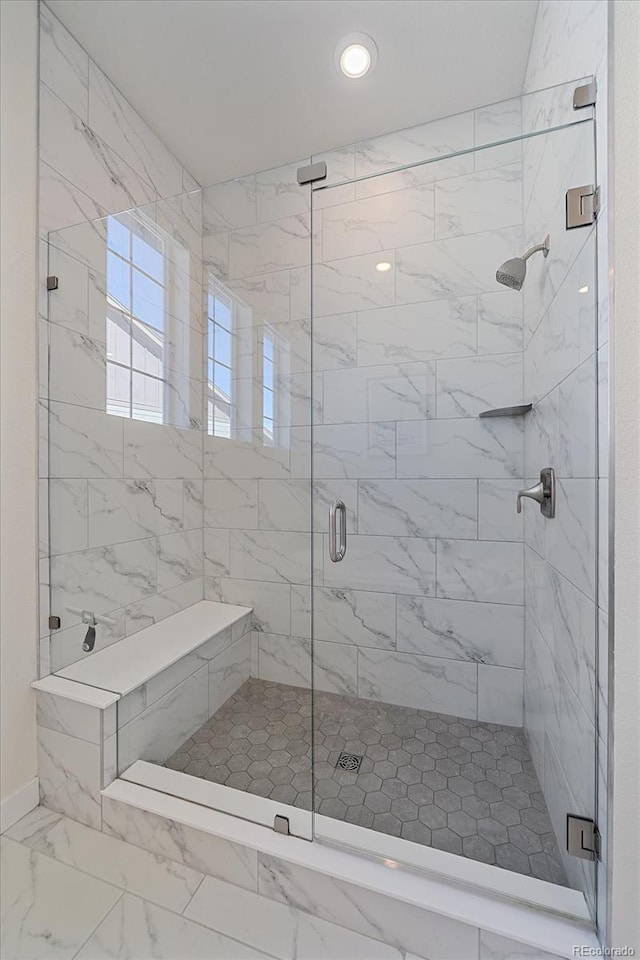 full bath with a shower stall and marble finish floor