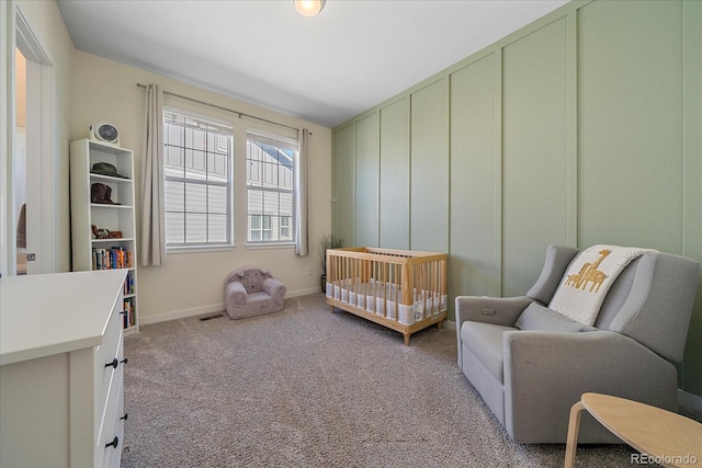 carpeted bedroom featuring visible vents, a crib, and baseboards