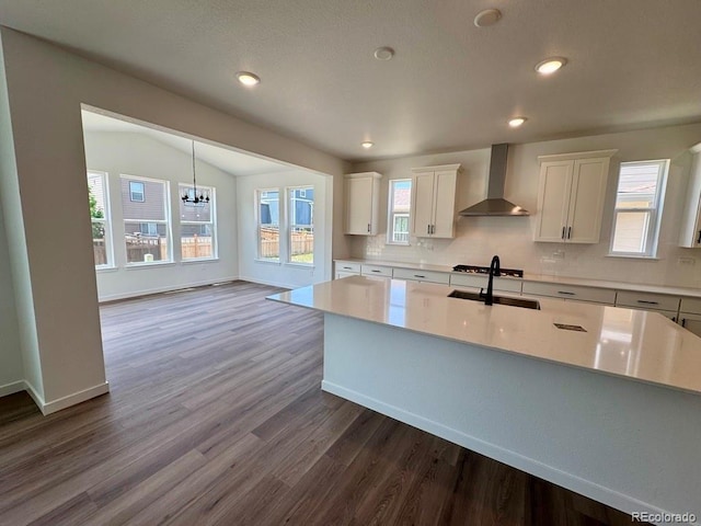 245 Wooten Ave, Brighton, CO 80601 - kitchen featuring wall chimney range hood, dark wood finished floors, tasteful backsplash, white cabinets, and light countertops