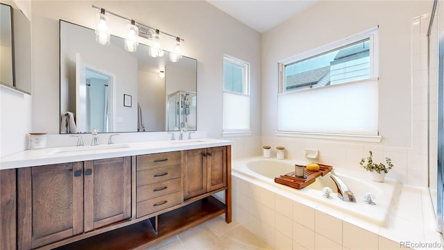 bathroom with vanity, a relaxing tiled tub, and tile patterned floors