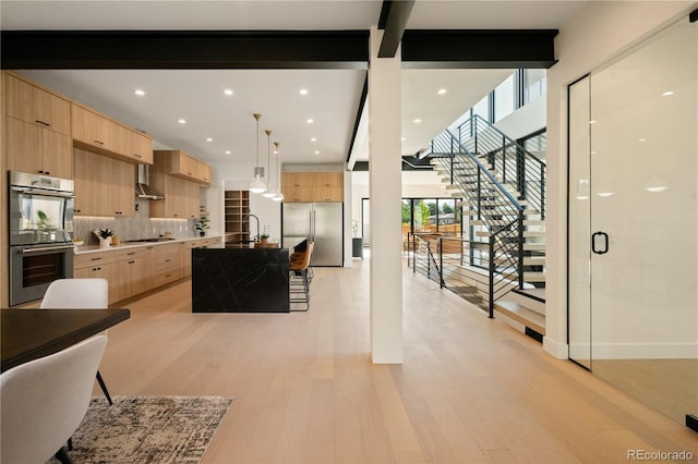 kitchen with sink, appliances with stainless steel finishes, a center island with sink, light brown cabinetry, and decorative light fixtures