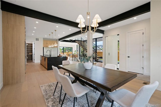 dining area featuring an inviting chandelier, light hardwood / wood-style flooring, and beamed ceiling