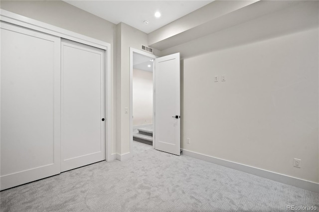 unfurnished bedroom featuring light carpet and a closet