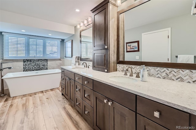 4505 S Yosemite St Unit 102, Denver, CO 80237 - full bathroom featuring tile walls, a freestanding tub, a sink, and double vanity