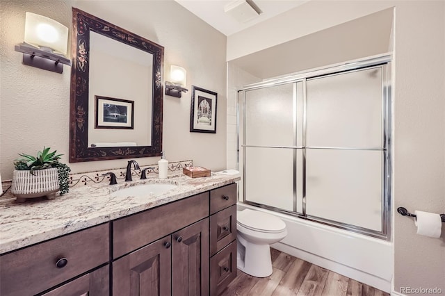 4505 S Yosemite St Unit 102, Denver, CO 80237 - bathroom featuring toilet, bath / shower combo with glass door, vanity, and wood finished floors