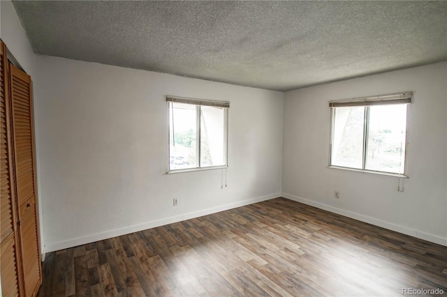 10211 Ura Ln Unit 9-308, Thornton, CO 80260 - unfurnished bedroom featuring multiple windows, wood finished floors, a closet, and a textured ceiling
