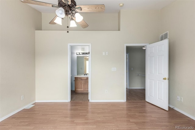 unfurnished bedroom featuring connected bathroom, light wood-style floors, visible vents, and baseboards