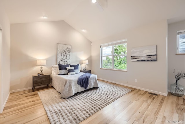 bedroom with light wood-style flooring, a ceiling fan, visible vents, vaulted ceiling, and baseboards