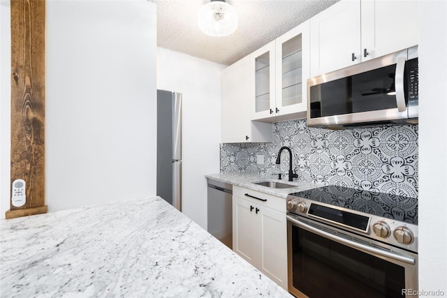 3035 Oneal Pkwy Unit 20V, Boulder, CO 80301 - kitchen with appliances with stainless steel finishes, a sink, light stone counters, tasteful backsplash, and glass insert cabinets