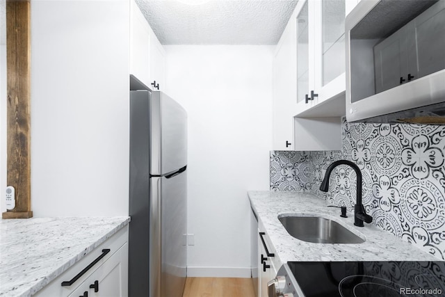 3035 Oneal Pkwy Unit 20V, Boulder, CO 80301 - kitchen featuring appliances with stainless steel finishes, backsplash, a sink, light stone countertops, and white cabinets