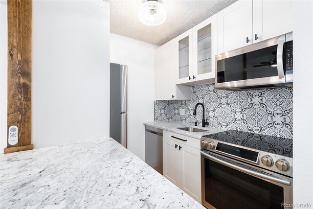 3035 Oneal Pkwy Unit 20V, Boulder, CO 80301 - kitchen featuring stainless steel appliances, a sink, light stone counters, backsplash, and glass insert cabinets