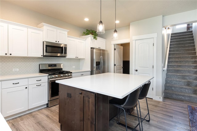 101 Wake St, Frederick, CO 80530 - kitchen with appliances with stainless steel finishes, light wood-style flooring, backsplash, a kitchen island, and light countertops