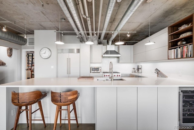 1610 Little Raven St Unit 302, Denver, CO 80202 - kitchen featuring built in fridge, wine cooler, wall chimney exhaust hood, modern cabinets, and light countertops