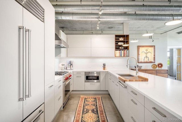 1610 Little Raven St Unit 302, Denver, CO 80202 - kitchen with high end appliances, a sink, open shelves, wall chimney exhaust hood, and light countertops