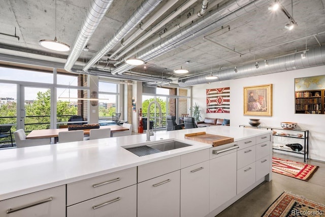 1610 Little Raven St Unit 302, Denver, CO 80202 - kitchen with a sink, light countertops, concrete flooring, white cabinets, and rail lighting