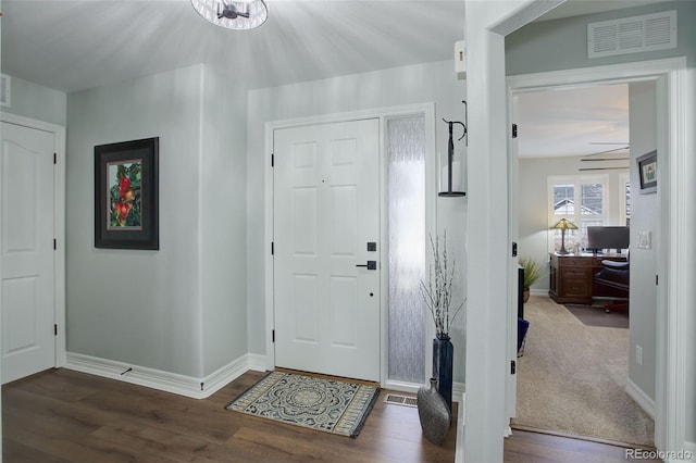 foyer featuring baseboards, visible vents, and wood finished floors