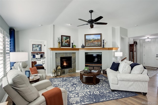 living room with baseboards, a tiled fireplace, a ceiling fan, lofted ceiling, and wood finished floors