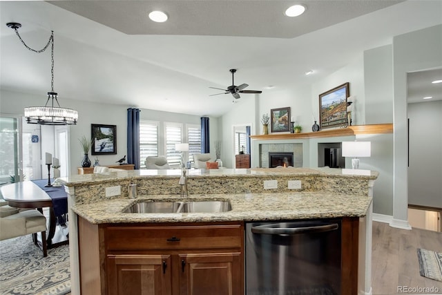 kitchen with stainless steel dishwasher, light wood-style floors, open floor plan, a kitchen island with sink, and a sink