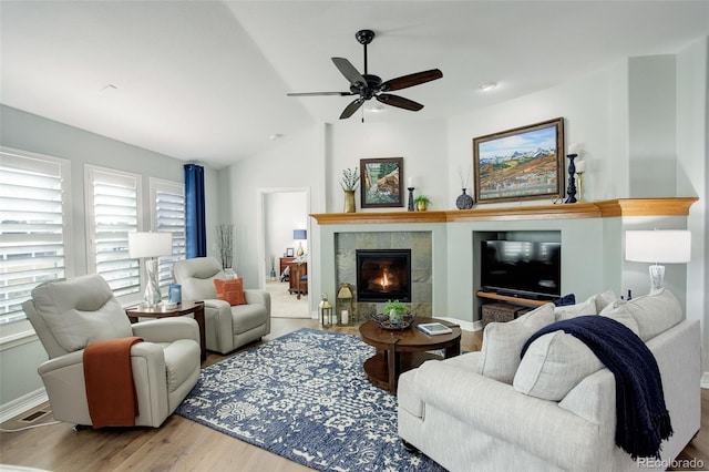 living room with a fireplace, lofted ceiling, a ceiling fan, wood finished floors, and baseboards