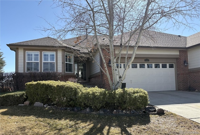 single story home with an attached garage, driveway, a shingled roof, and brick siding