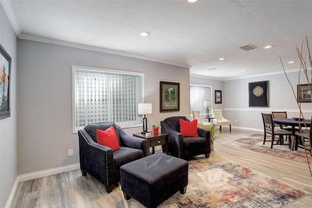 living room featuring baseboards, ornamental molding, visible vents, and light wood-style floors