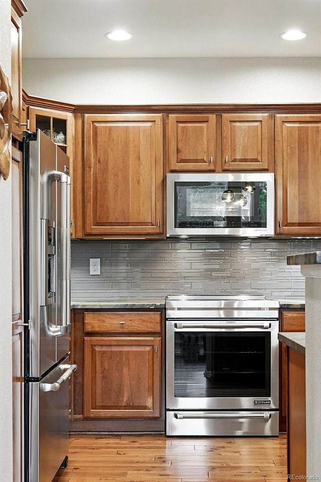681 W Burgundy St Unit A, Highlands Ranch, CO 80129 - kitchen featuring appliances with stainless steel finishes, brown cabinetry, backsplash, light wood-style floors, and recessed lighting