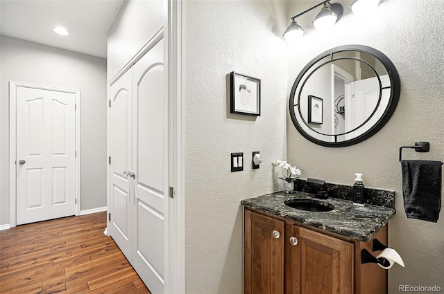 681 W Burgundy St Unit A, Highlands Ranch, CO 80129 - bathroom with vanity, wood finished floors, a textured wall, baseboards, and recessed lighting