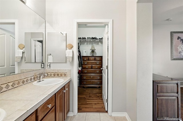 681 W Burgundy St Unit A, Highlands Ranch, CO 80129 - full bath featuring double vanity, a spacious closet, tile patterned floors, tasteful backsplash, and baseboards