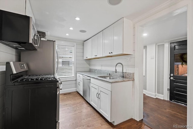 kitchen featuring sink, light wood-type flooring, stainless steel appliances, light stone countertops, and white cabinets