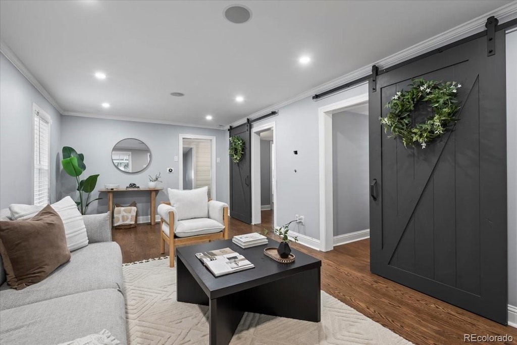 living room with hardwood / wood-style floors, a barn door, and ornamental molding