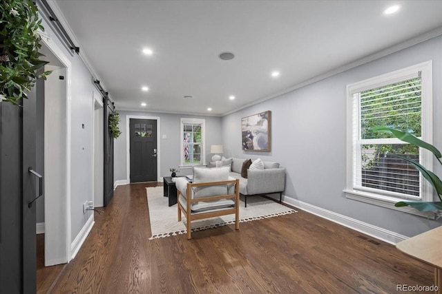 living room with dark hardwood / wood-style flooring, ornamental molding, and a barn door