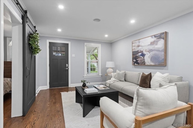 living room with dark wood-type flooring, ornamental molding, and a barn door