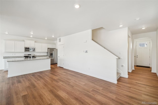 kitchen with white cabinetry, a kitchen island with sink, light hardwood / wood-style flooring, and appliances with stainless steel finishes