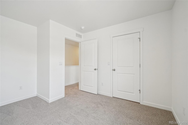 unfurnished bedroom featuring light carpet and a closet